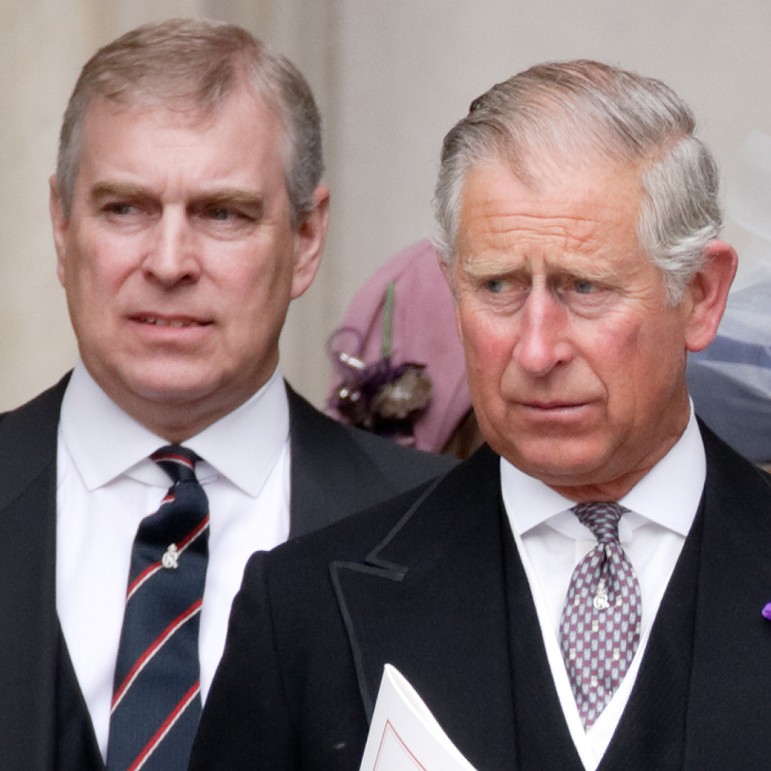 Prince Andrew wears a suit and stands behind King Charles