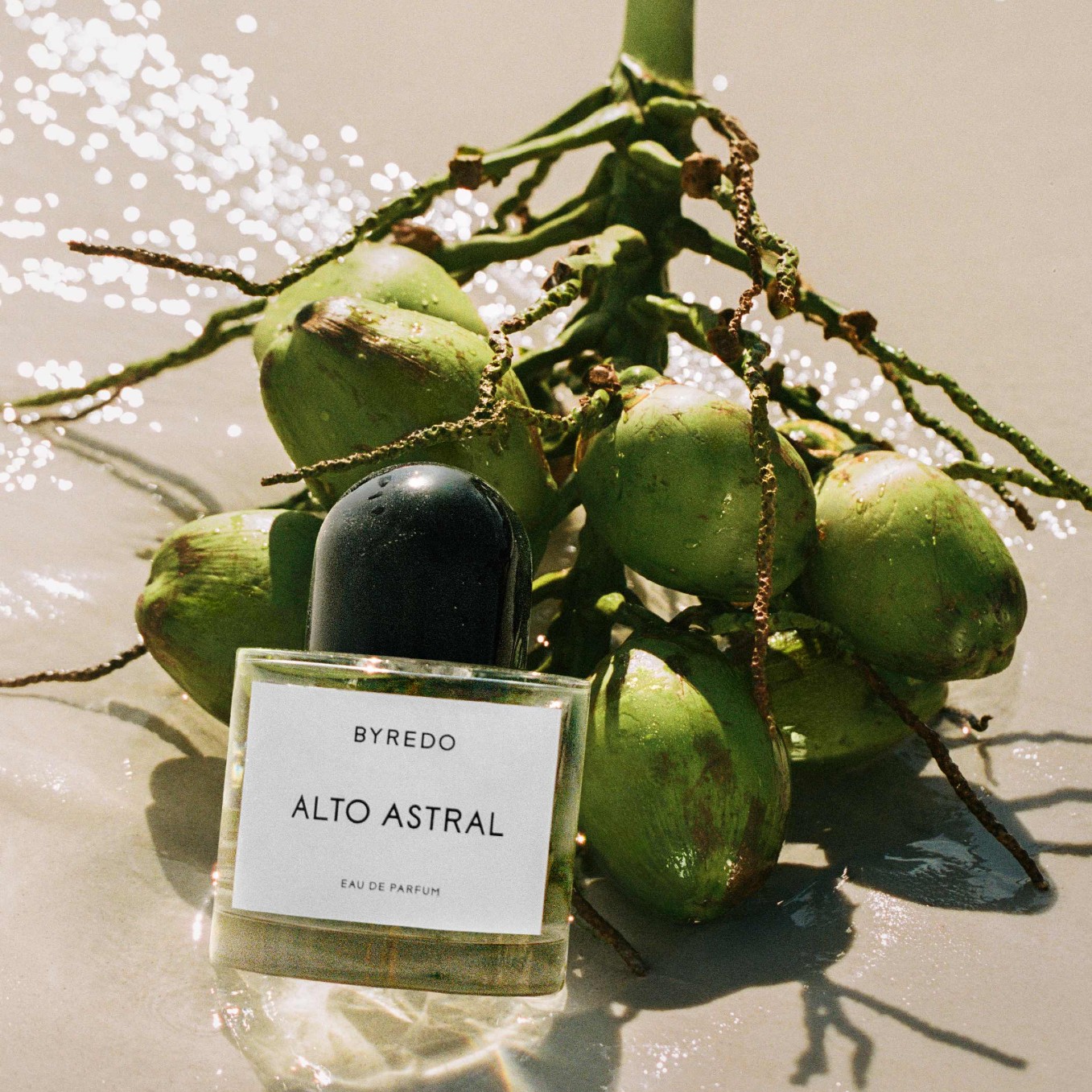 a bottle of perfume next to a pile of coconuts