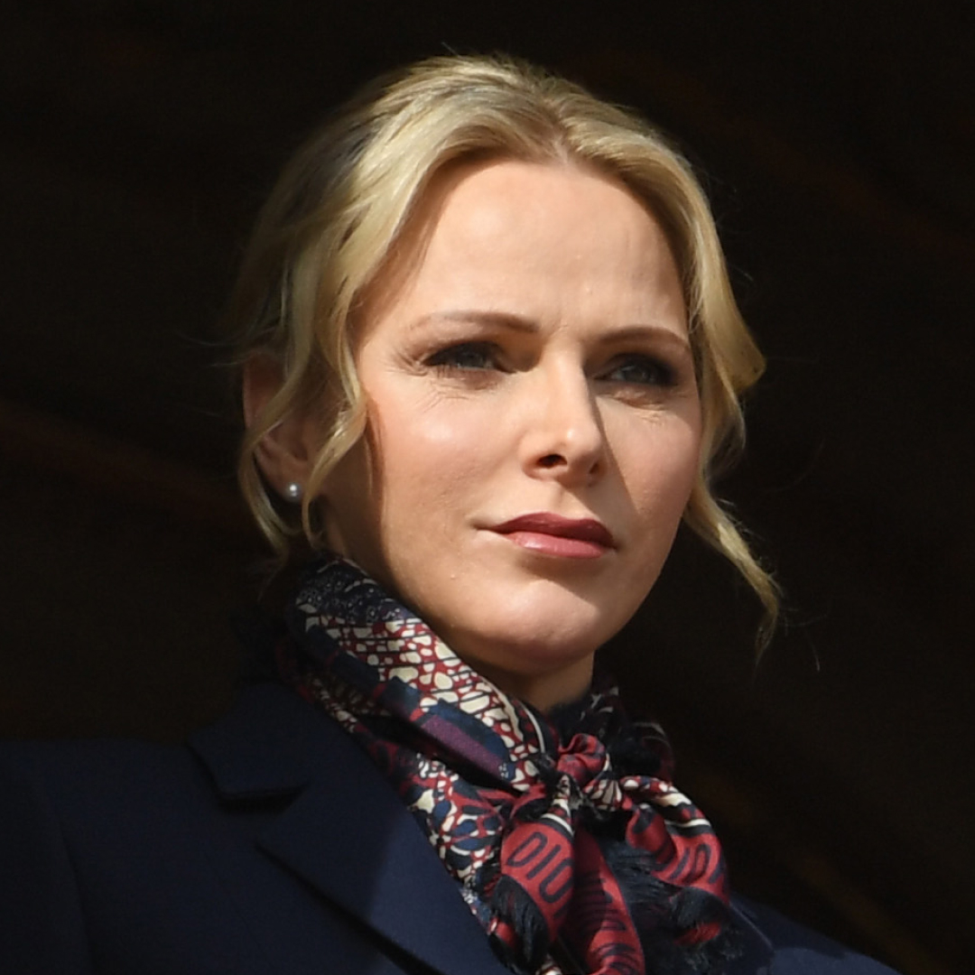 Princess Charlene wears a silk scarf and coat and wears her hair tied back