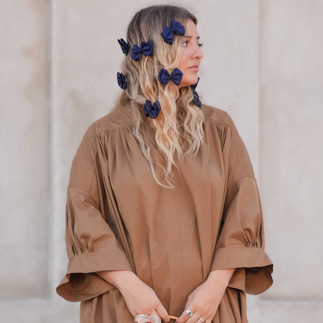 Woman with bows in her hair posing with face away from the camera.